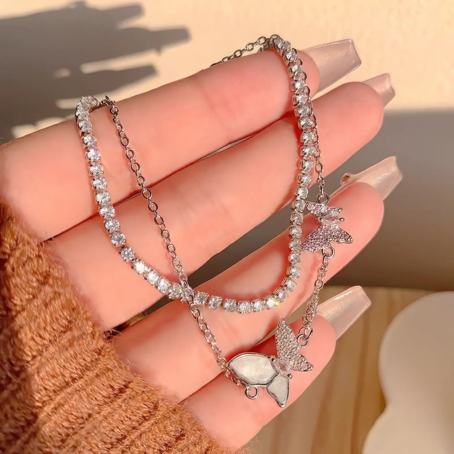 Double - layer butterfly bracelet held in hand, showcasing butterfly and chain details.