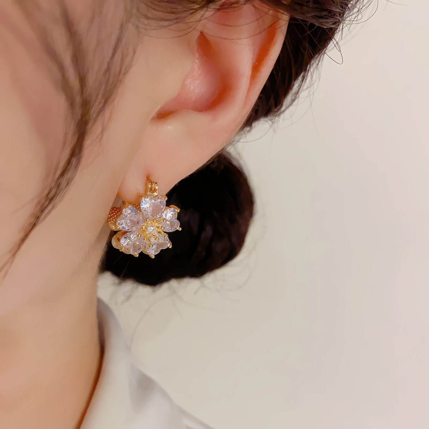 Double - sided flower earrings featuring zircon and cat's eye stone, worn, showcasing the sparkling and elegant design on the ear.