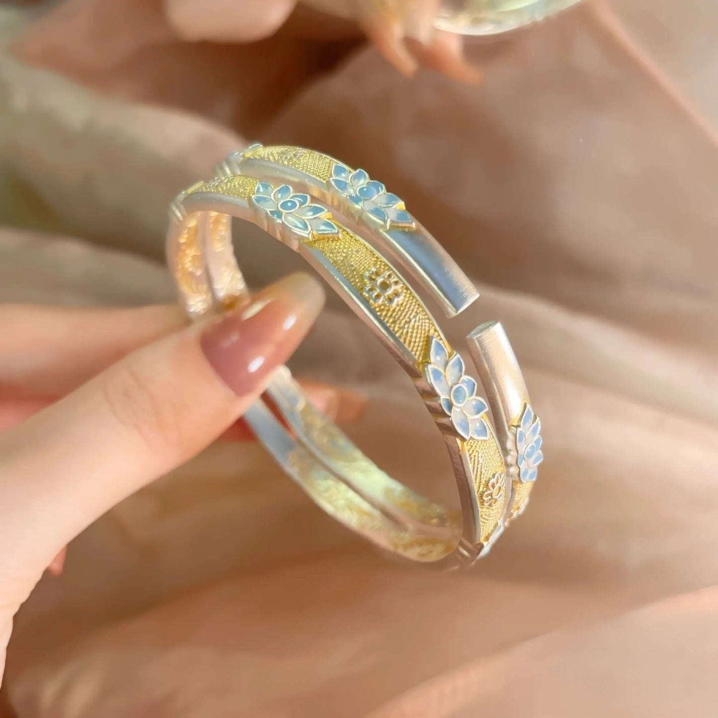 Close - up of enamel blue lotus bracelet, showing detailed blue lotus and gold - toned elements.