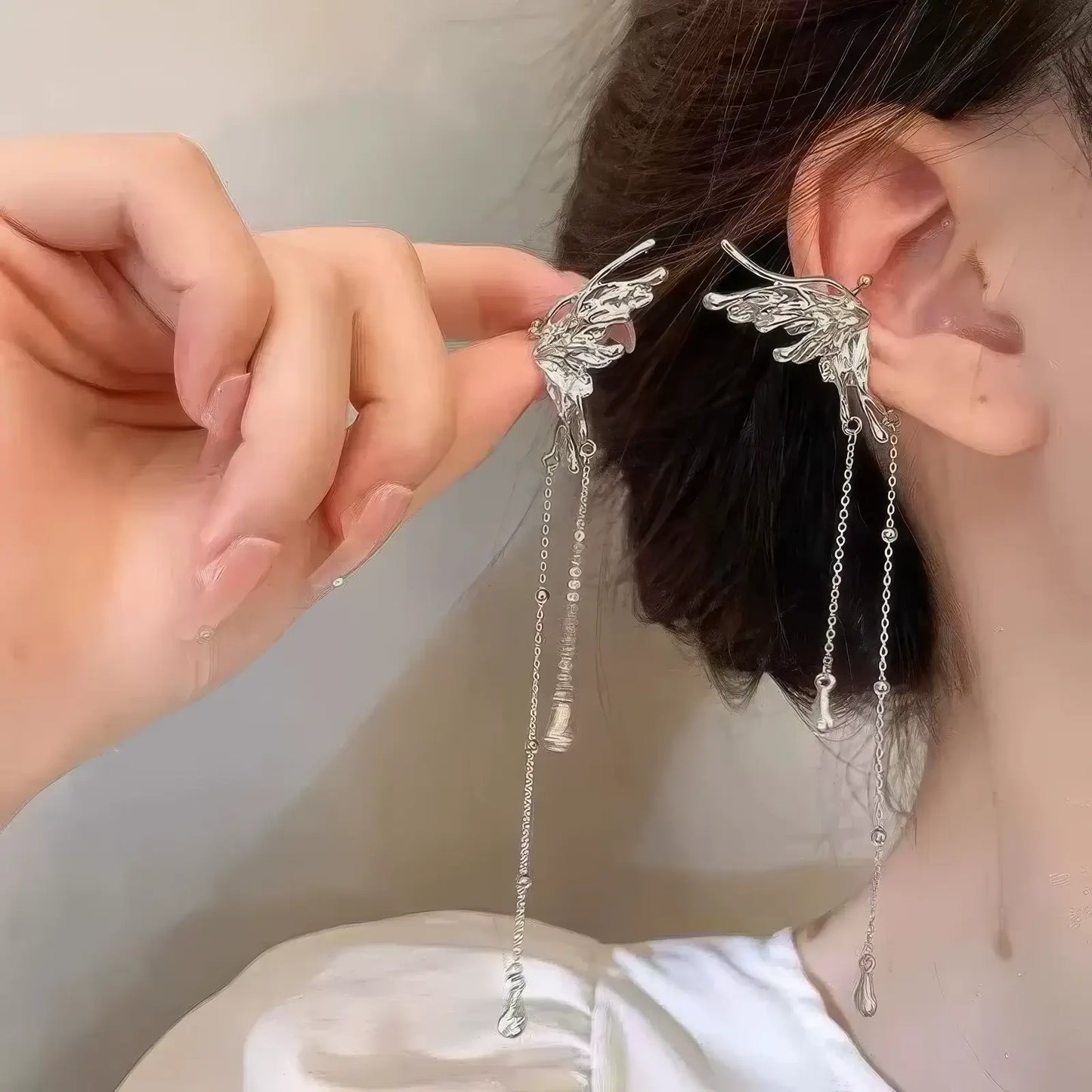 Hand adjusting the fairy ear butterfly ear clip from another angle, showing the overall structure and how it fits on the ear.