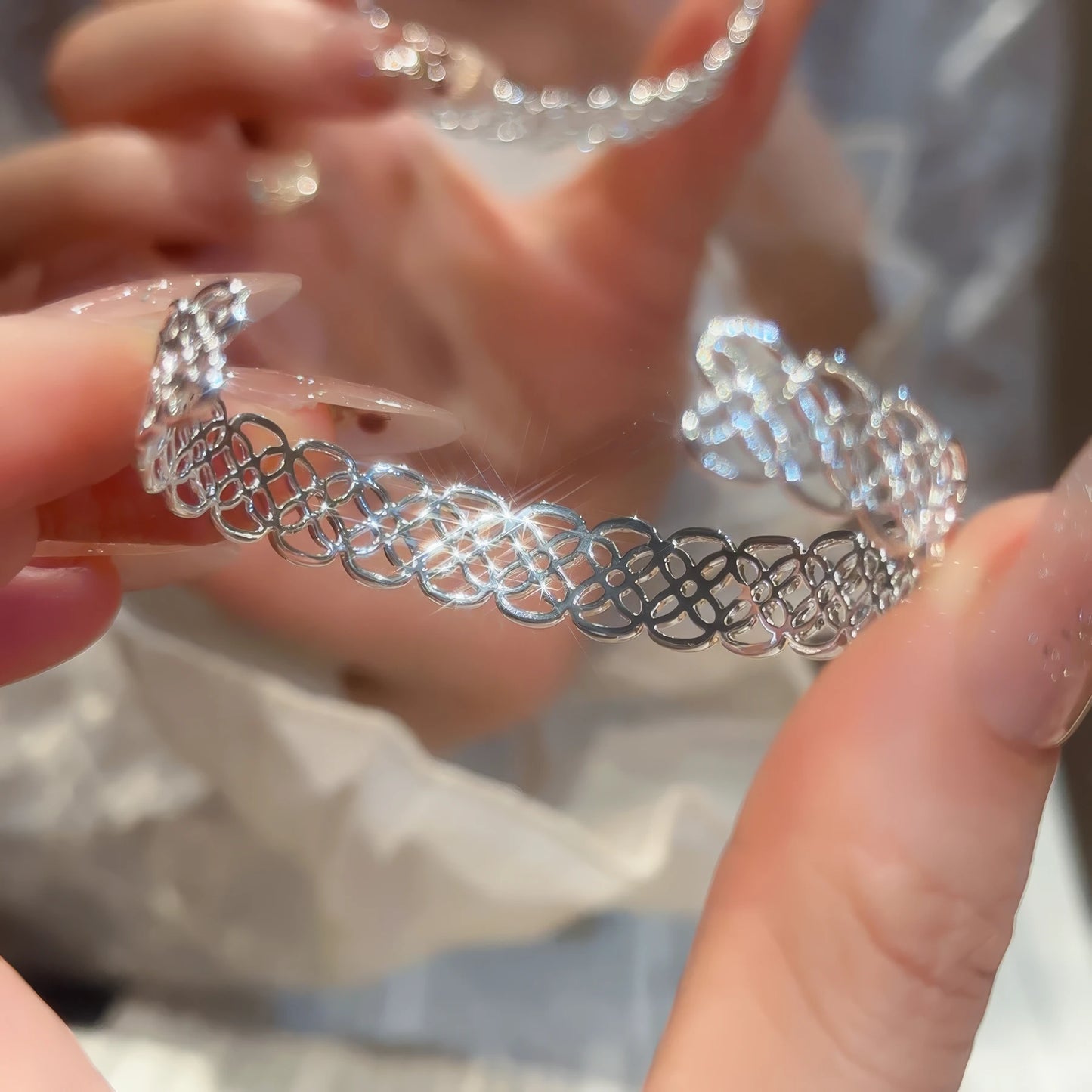 Silver flower hollow - out open bracelet held in hand, showcasing hollow - out details.