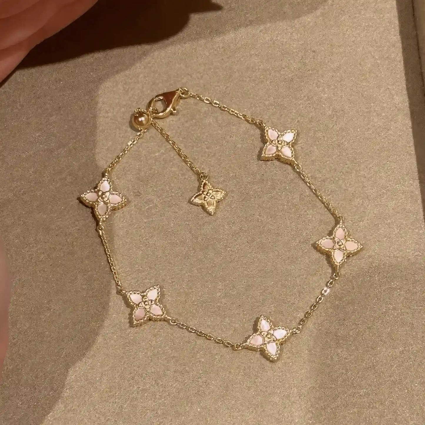 Flower petal pendant bracelet placed on light - colored fabric.