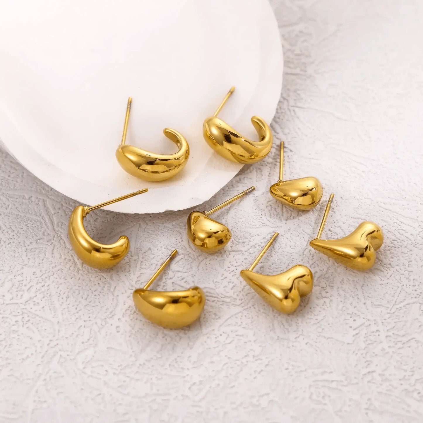 Assortment of gold teardrop heart stud earrings displayed on plate