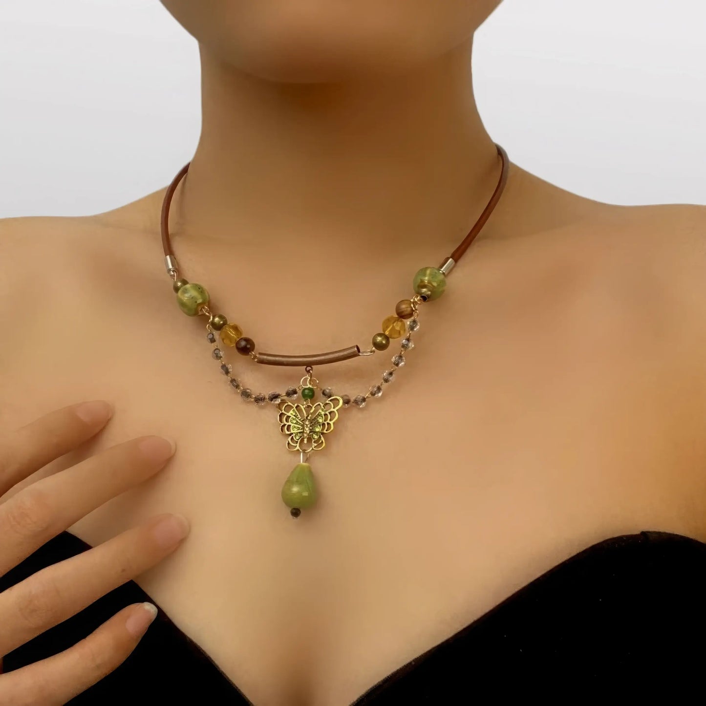 Green butterfly water drop pendant necklace worn, with hand near the necklace