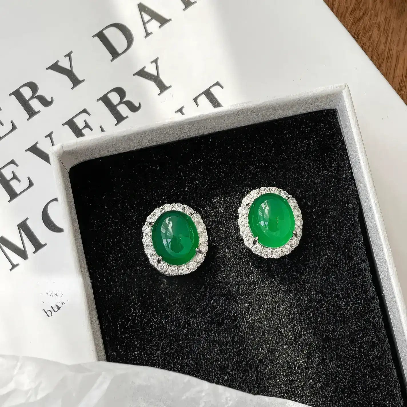 Pair of green chalcedony micro - inlaid stud earrings in a black - lined box with paper background