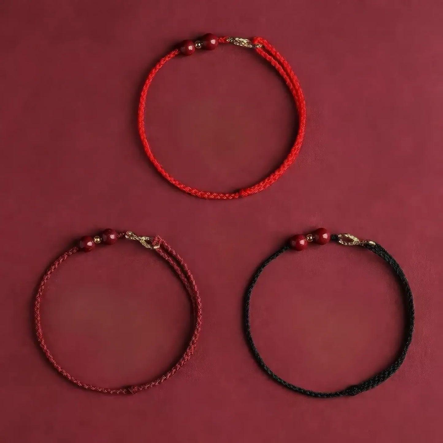 Set of "infinite wealth" red string bracelets in red, dark red, and black, on a red background.