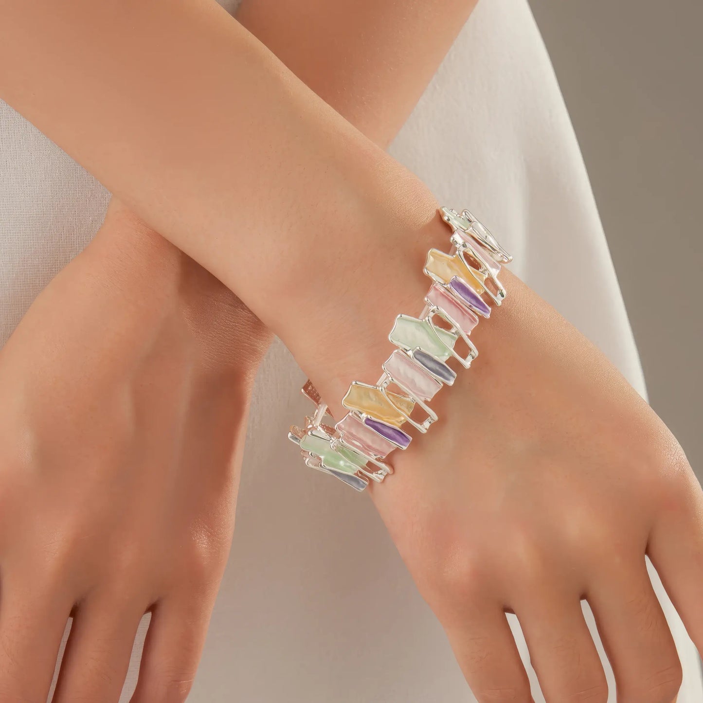 Irregular colorful enamel bracelet worn on wrist, with a sleeveless arm.