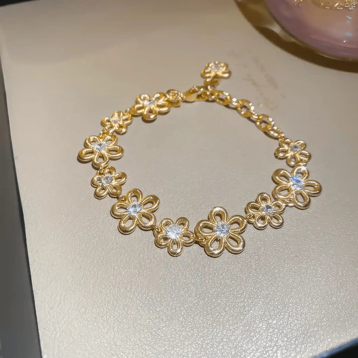 Irregular flower metal bracelet placed on a light - colored surface.