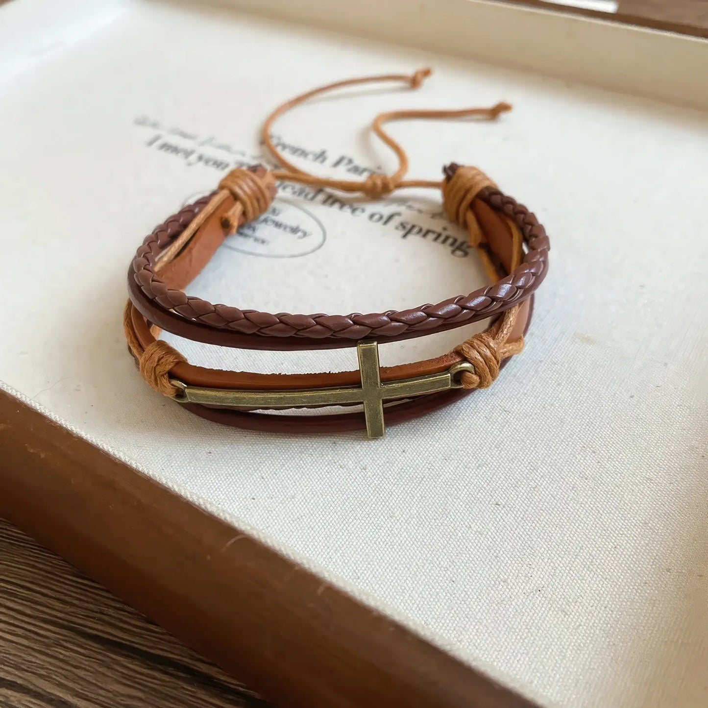 Leather cross braided bracelet placed on a tray with a beige surface.