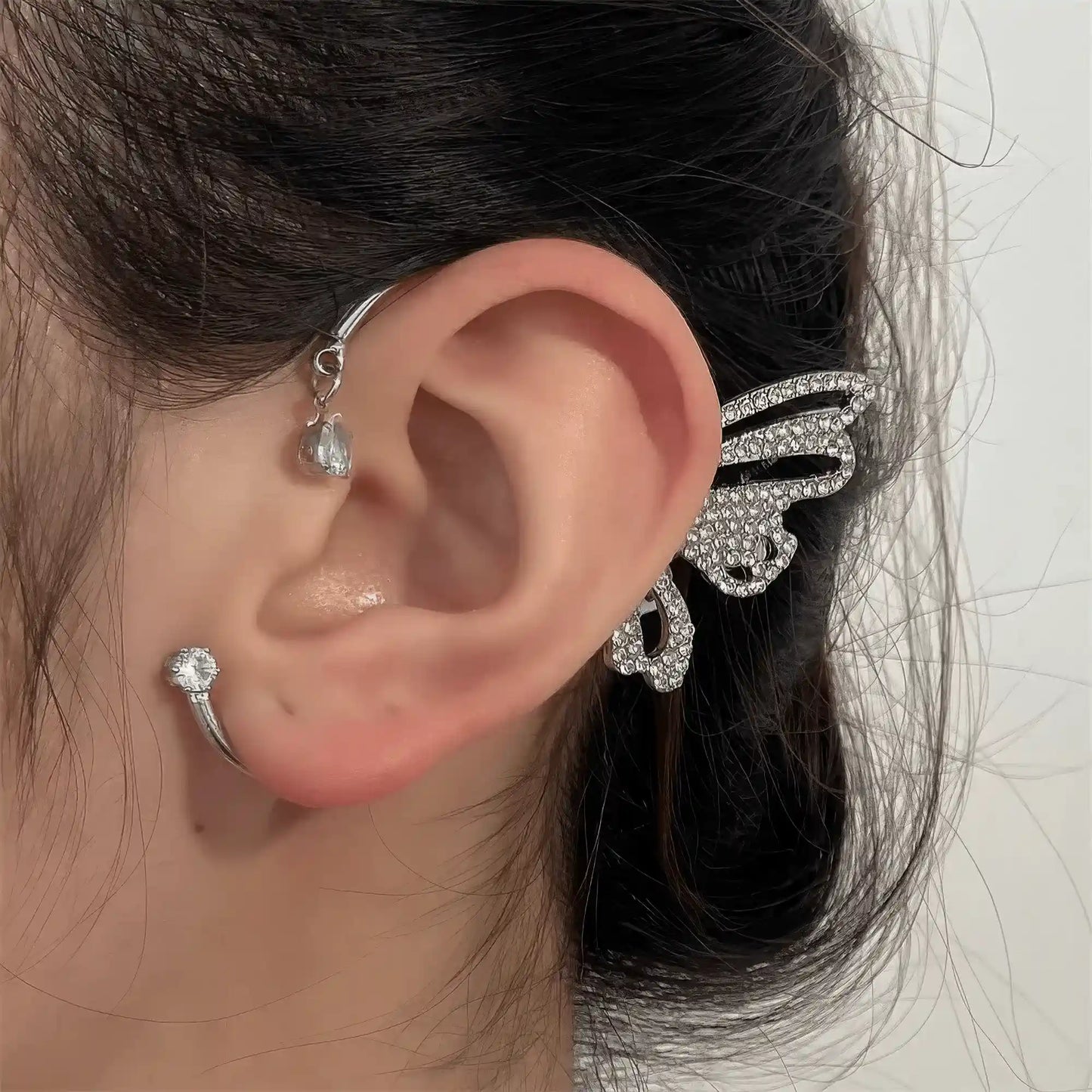 Metal diamond - inlaid butterfly ear cuff worn on ear, with a side - view showing the earring's details.