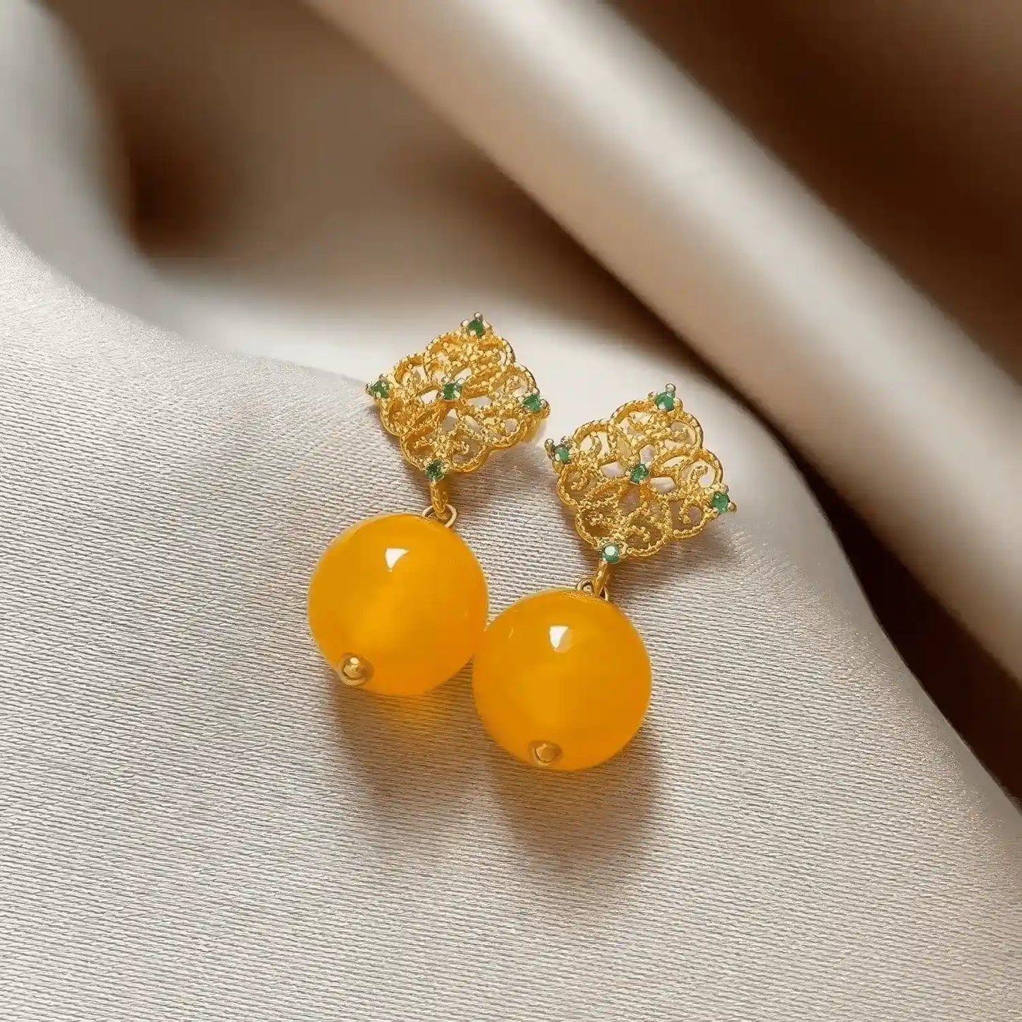 Pair of neo - Chinese style yellow bead earrings, displayed on a textured surface, highlighting the intricate golden filigree and yellow bead structure.