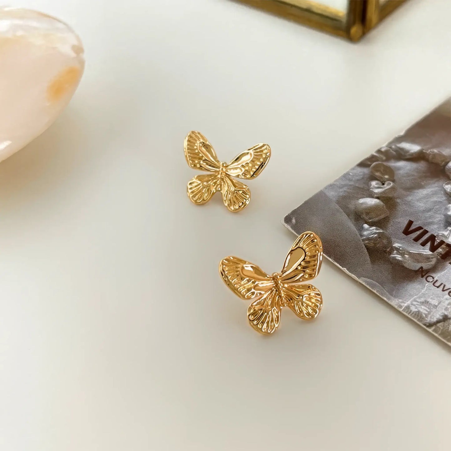 Gold neo - Chinese textured butterfly stud earrings placed with decorative items