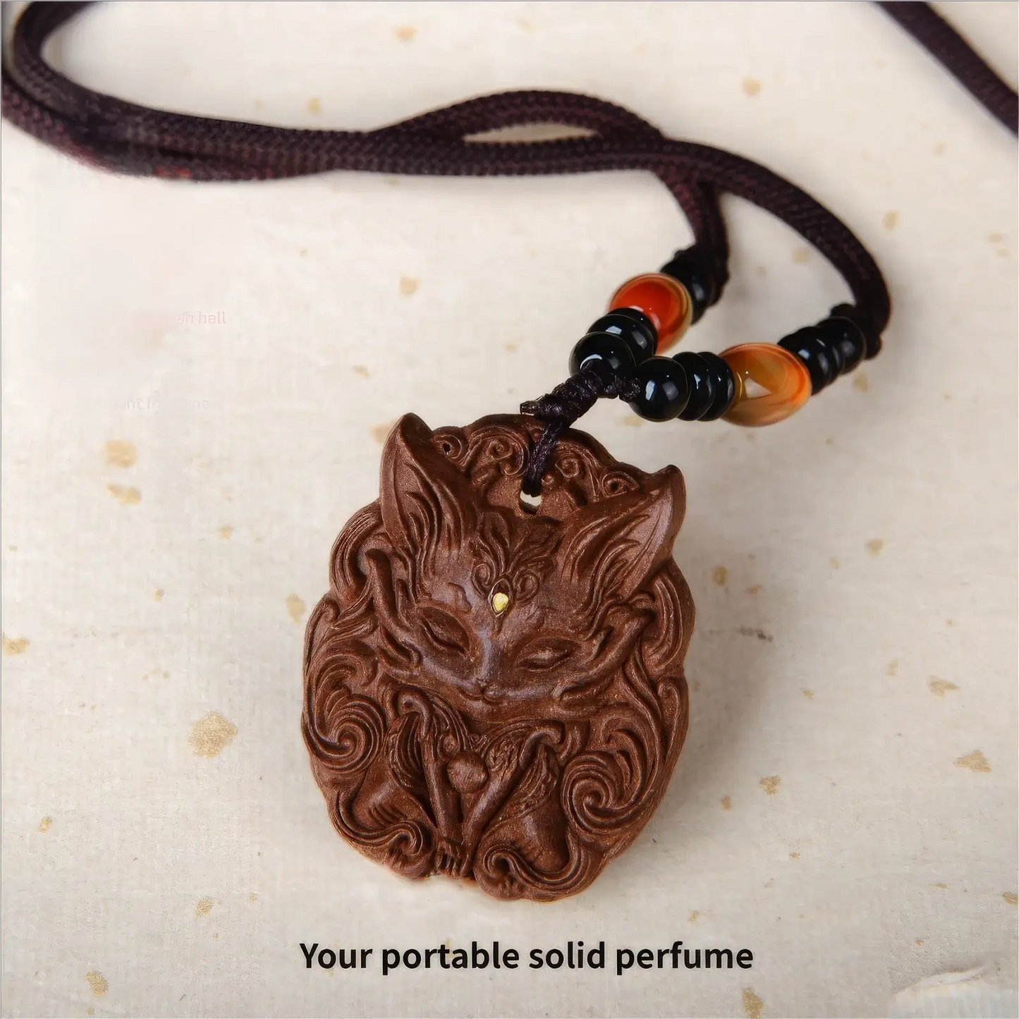 Another angle view of a nine - tailed fox incense pendant on a cord with black, orange, and other colored beads, emphasizing the intricate patterns on the brown pendant.
