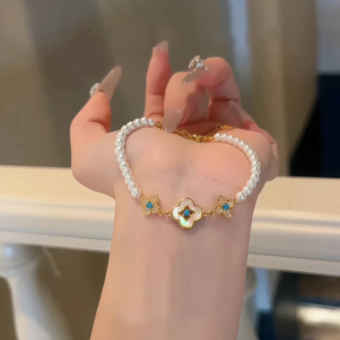 Pearl bracelet with neo - Chinese decorative elements, held in hand.