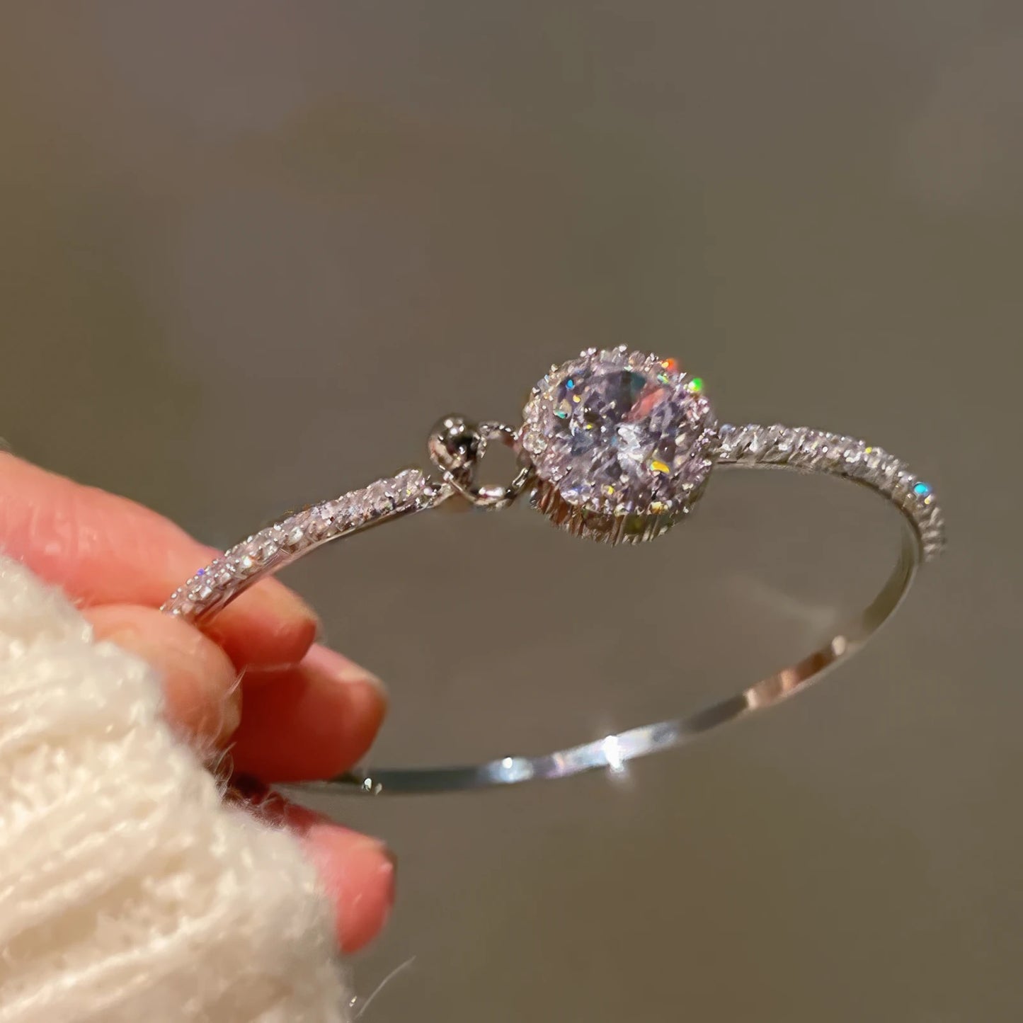 Popular super - shiny round zircon bracelet held in hand, showcasing the sparkling central zircon and surrounding detailing.