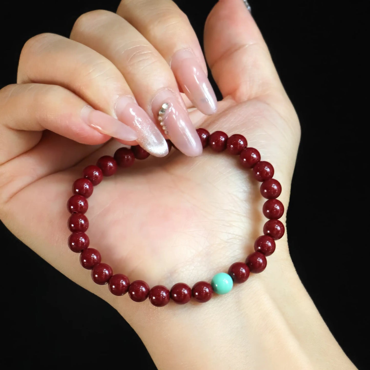 Purple gold cinnabar bead bracelet held in hand, showing detailed bead arrangement.