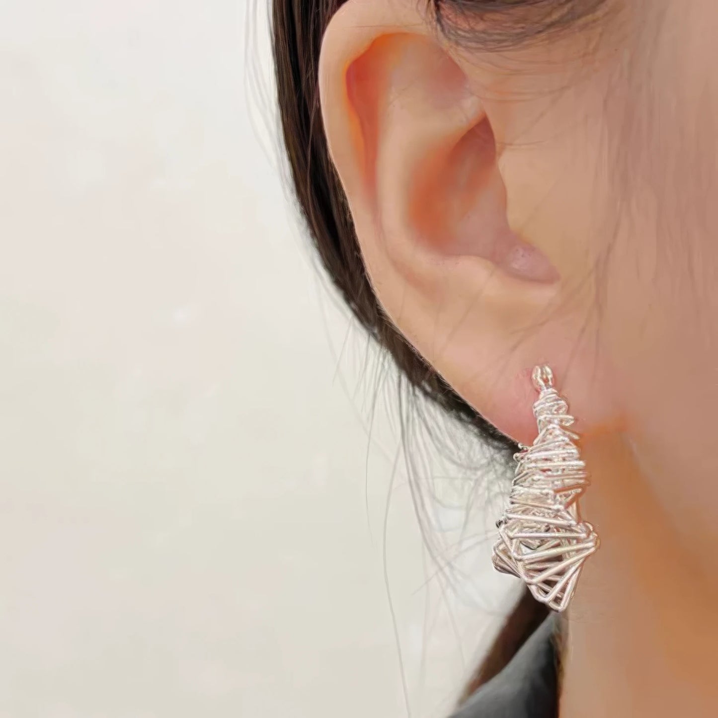 Silver wrapped metal circle earring worn, showcasing the bold, twisted look on the ear