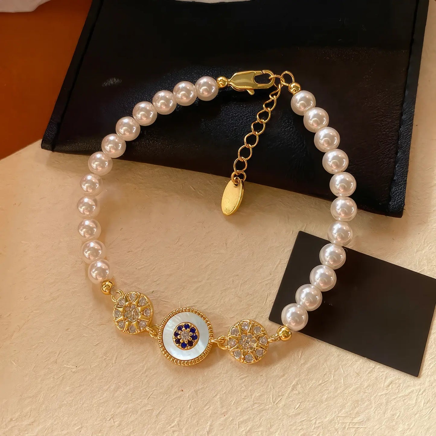 Zircon pearl beaded bracelet placed on a surface with a black pouch and card.
