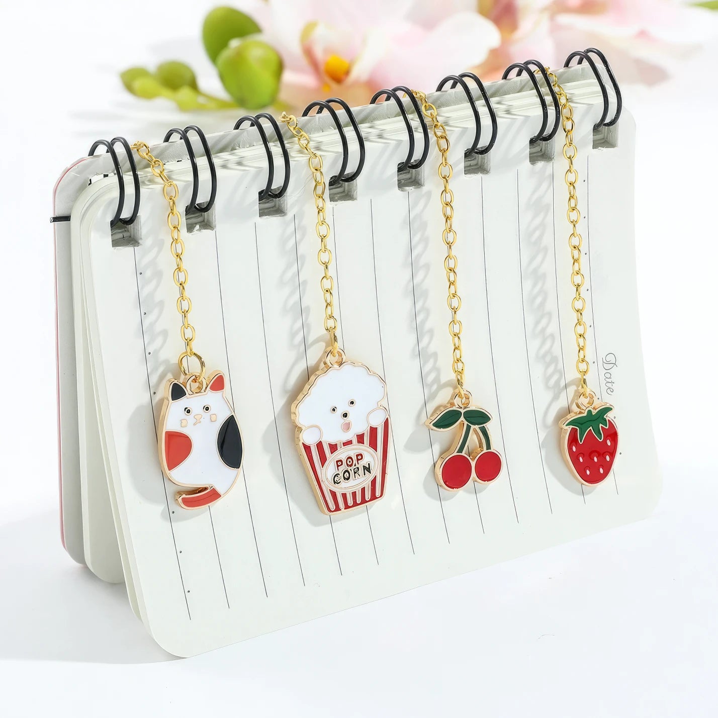 Multiple animal and plant themed bookmarks with golden chains, displayed on notebook, light background