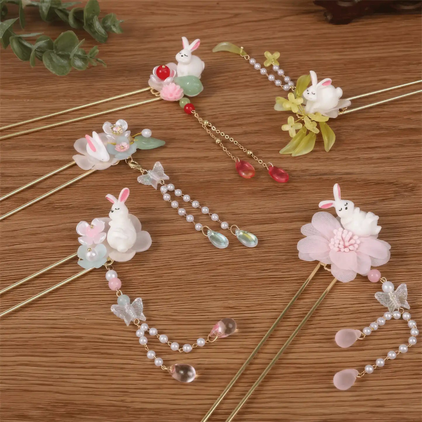 Set of Baituigui hairpins with rabbit, floral and tassel designs, wooden background