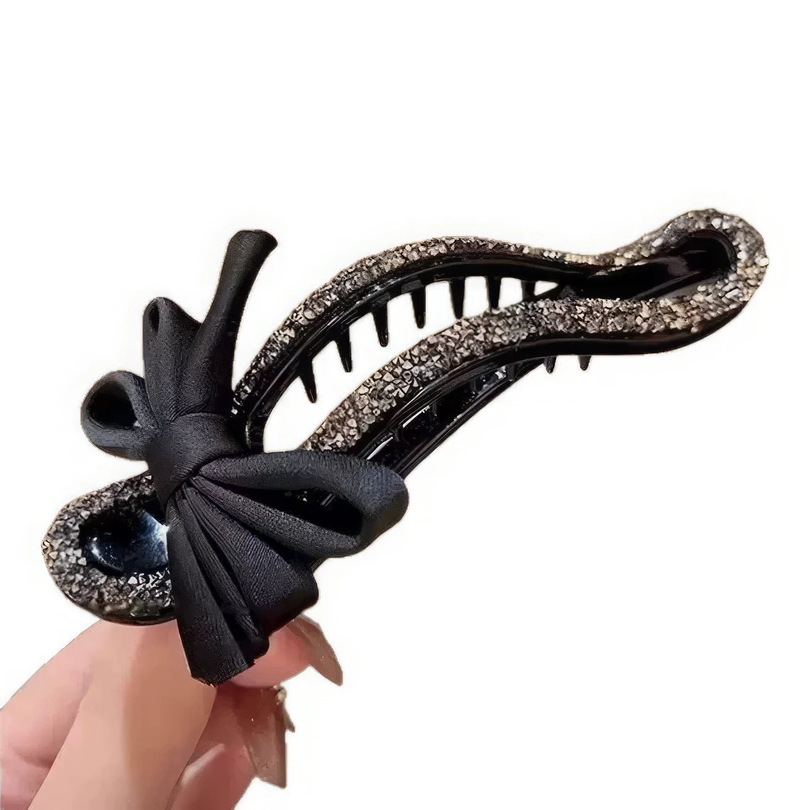 Hand holding black bow rhinestone hair clip, white background