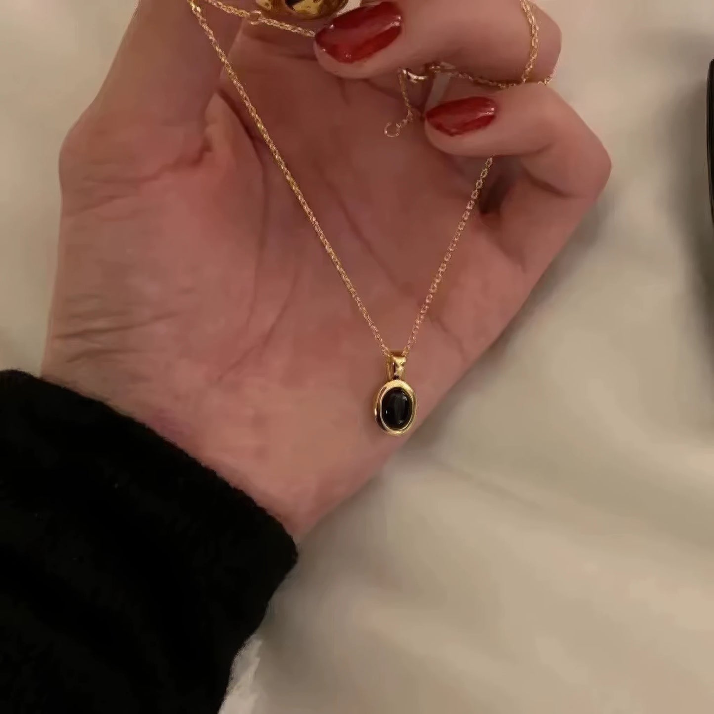 Hand holding black pendant necklace, highlighting craftsmanship