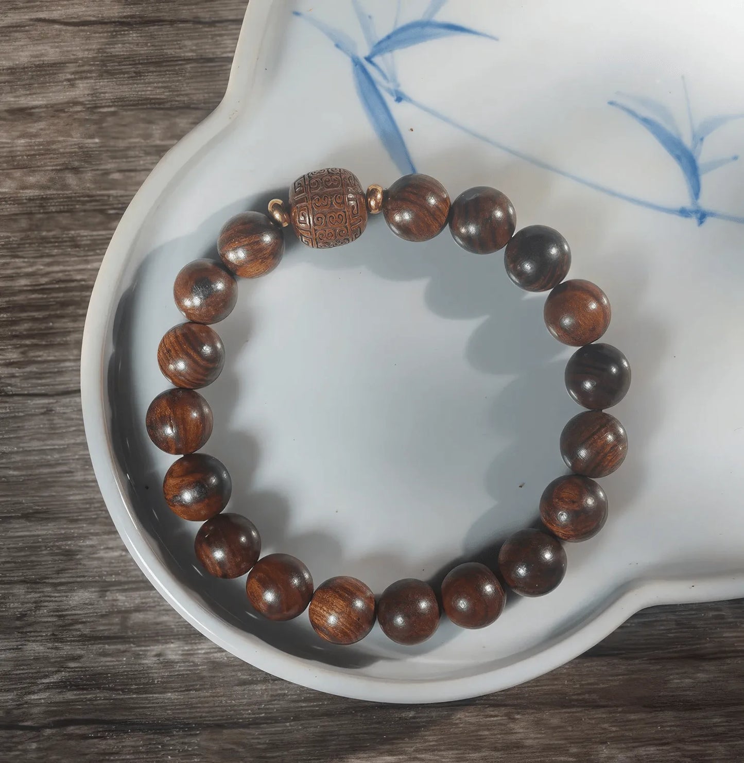 Black rosewood cloud - pattern bracelet placed on white plate with blue pattern