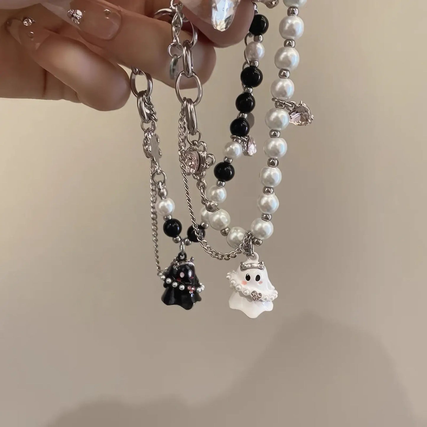 Hands holding black and white ghost bracelets with beads