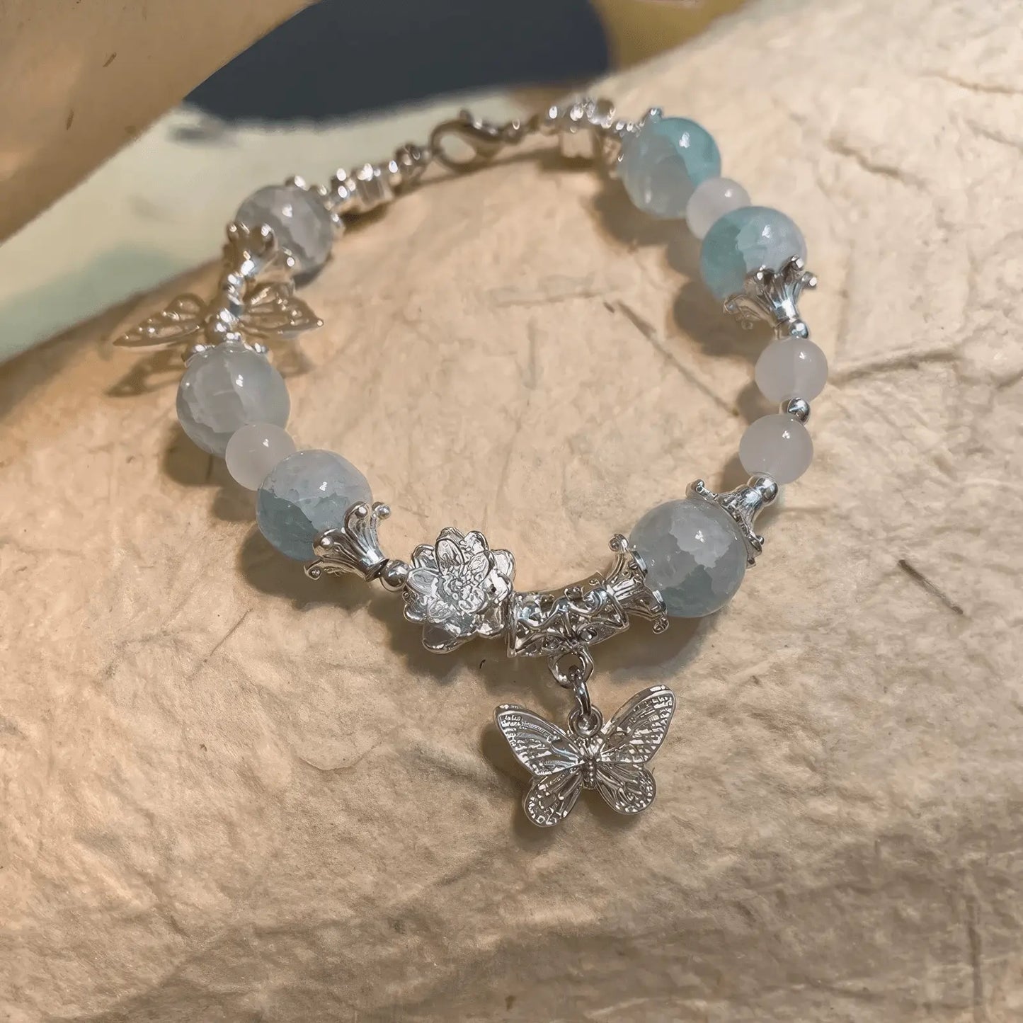 Side view of blue butterfly beaded bracelet placed on fabric, emphasizing details