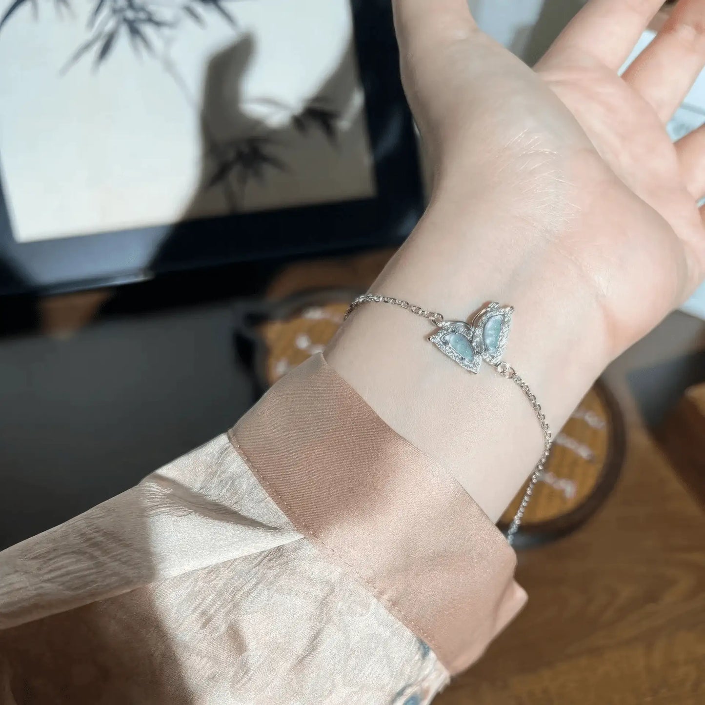Blue butterfly - shaped silver bracelet on wrist, with a light - colored sleeve