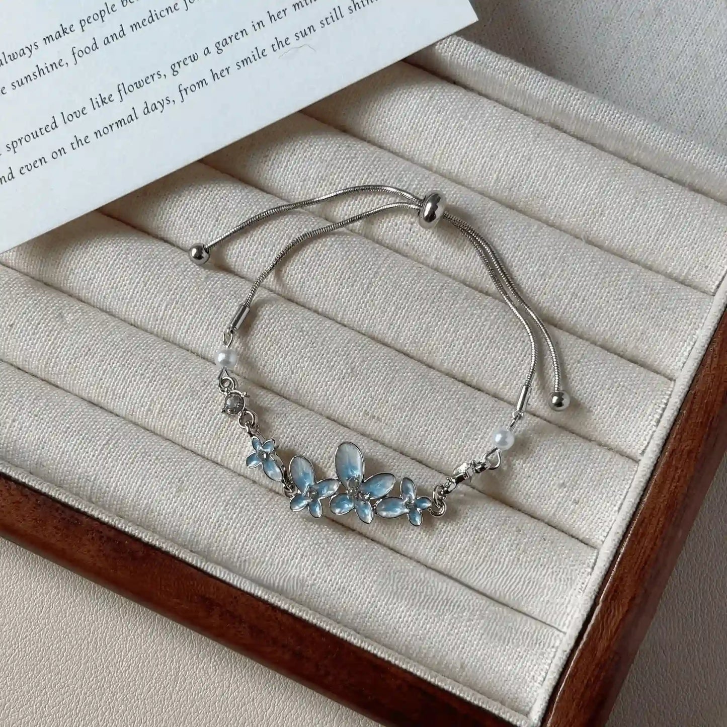 Blue butterfly glaze bracelet placed on a beige jewelry tray with a white paper