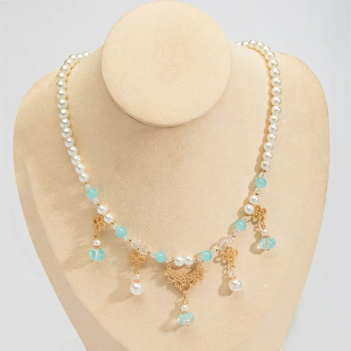 Blue pumpkin bead necklace with pearls and gold details, displayed on mannequin, light background