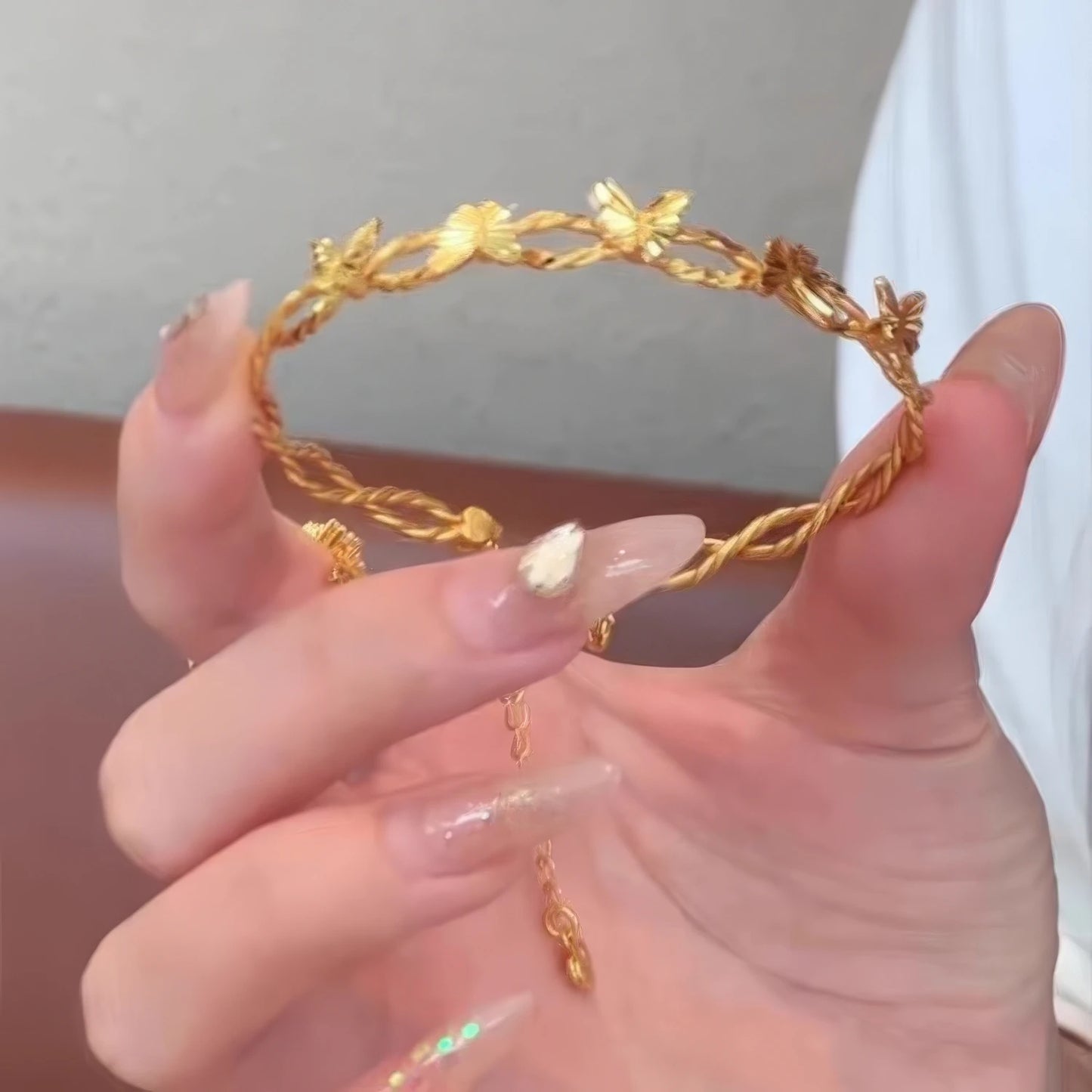 Hand holding gold butterfly bracelet, highlighting craftsmanship