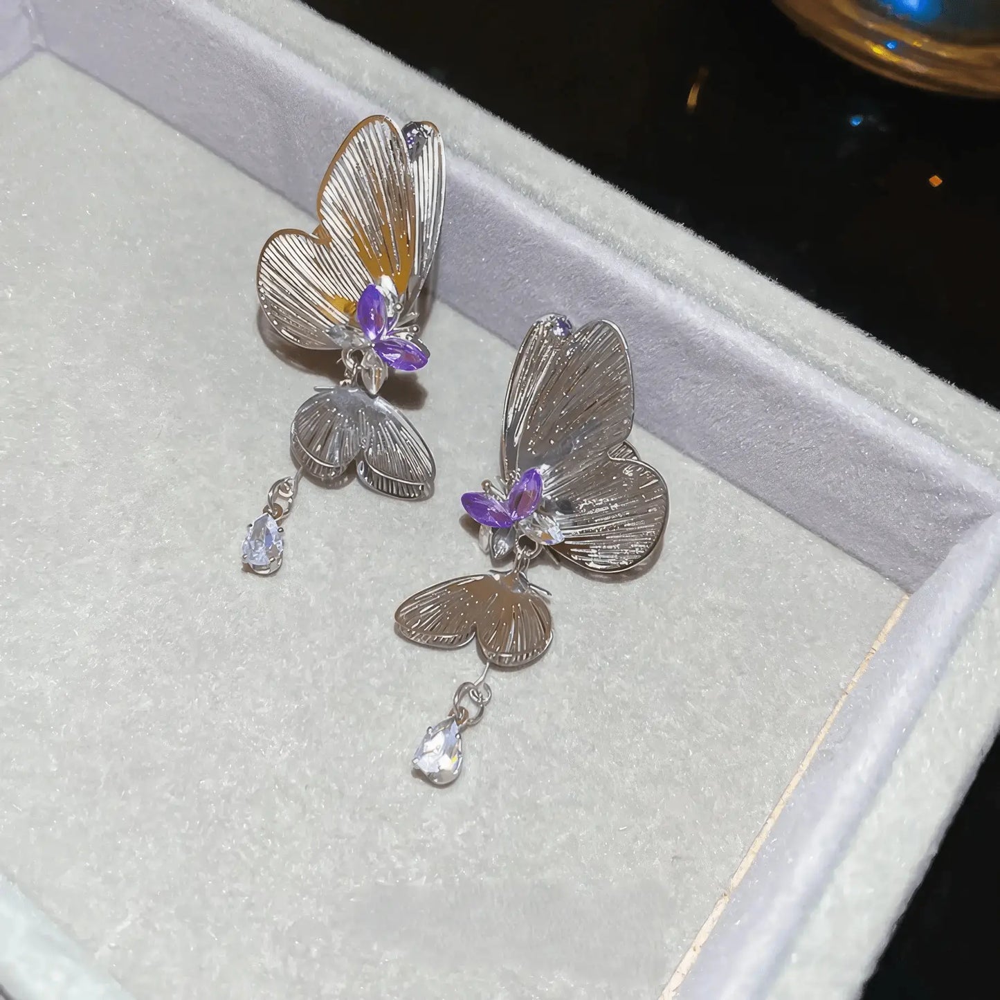Butterfly long tassel earrings displayed in a gray jewelry box