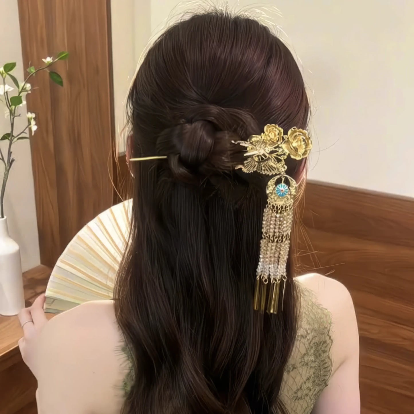 Butterfly-peony tassel hairpin worn in updo with green halter top, side-back view