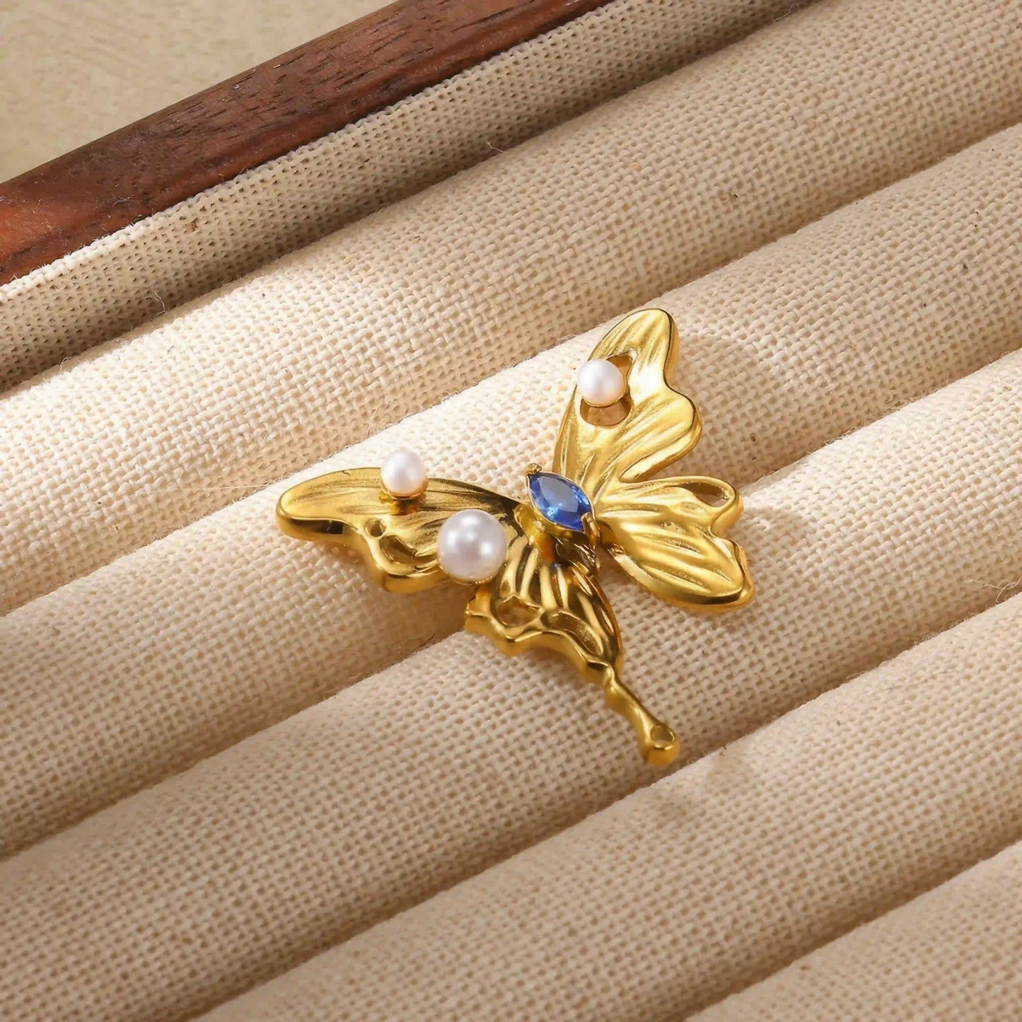 Titanium steel butterfly brooch placed on beige fabric, showcasing style