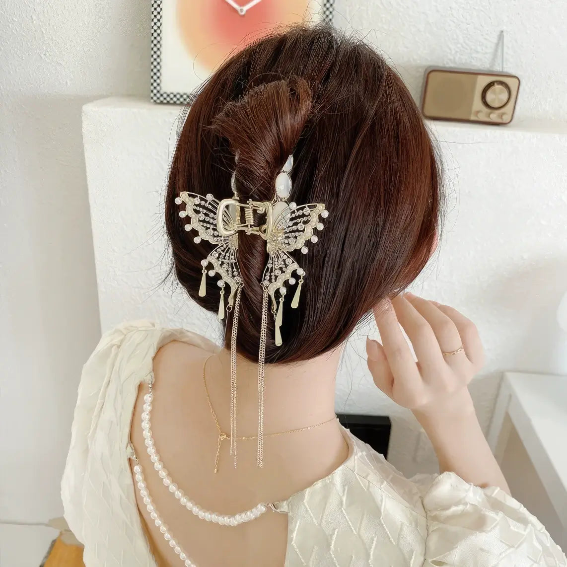 Cat - eye stone butterfly claw clip worn in an updo hairstyle, light clothing background