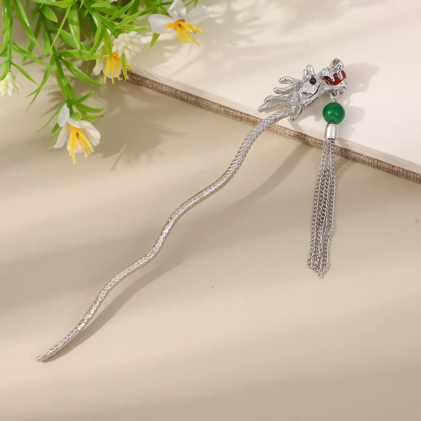 Chengyunqi silver hairpin with dragon design and tassel, beige background with greenery