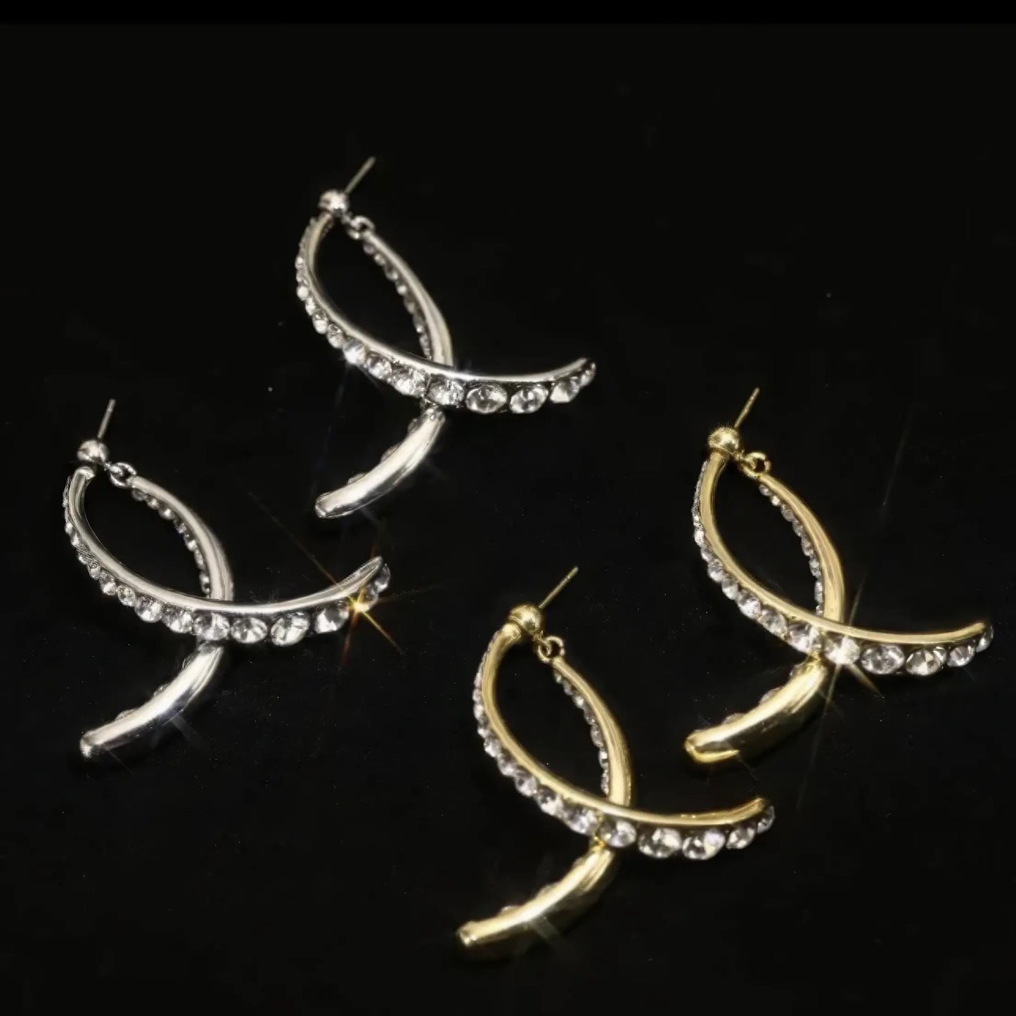 Cross diamond earrings in silver and gold, isolated on black background