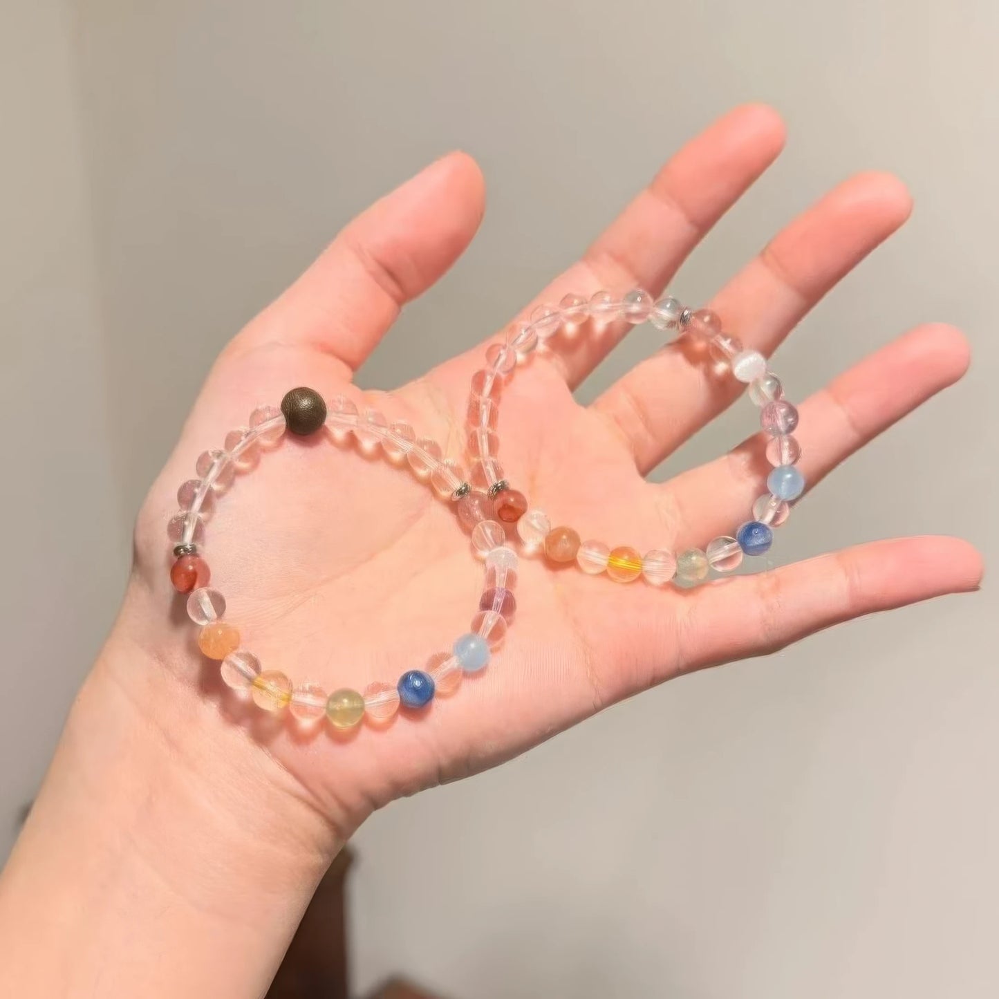 Hand holding two dopamine rainbow candy beaded bracelets, highlighting design details