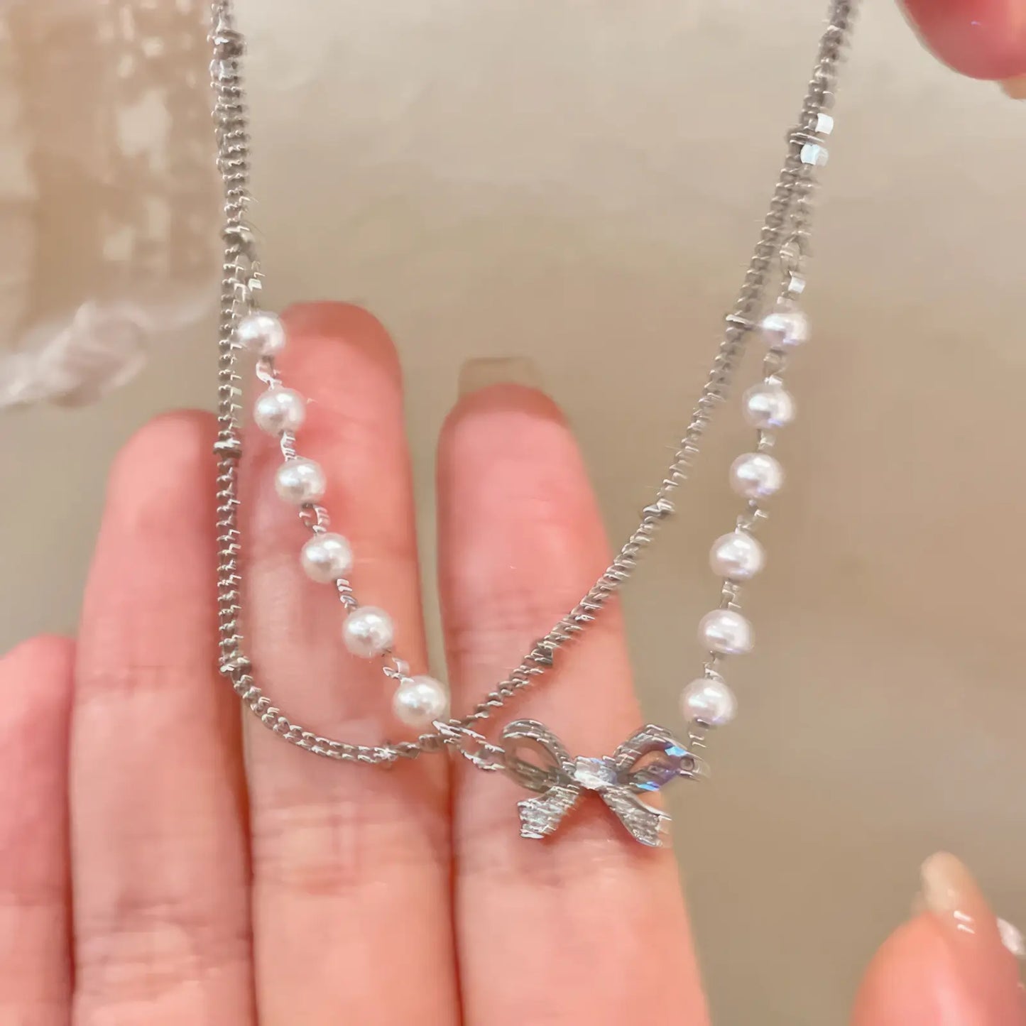 Holding double - layer bow pearl bracelet, showcasing design