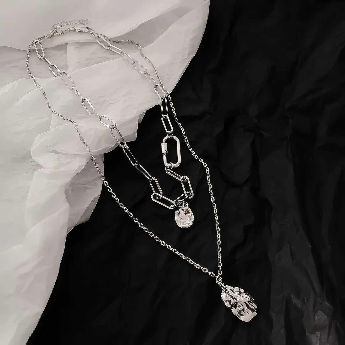 Double - layer irregular necklace worn, paired with a black garment and white fabric, showcasing style