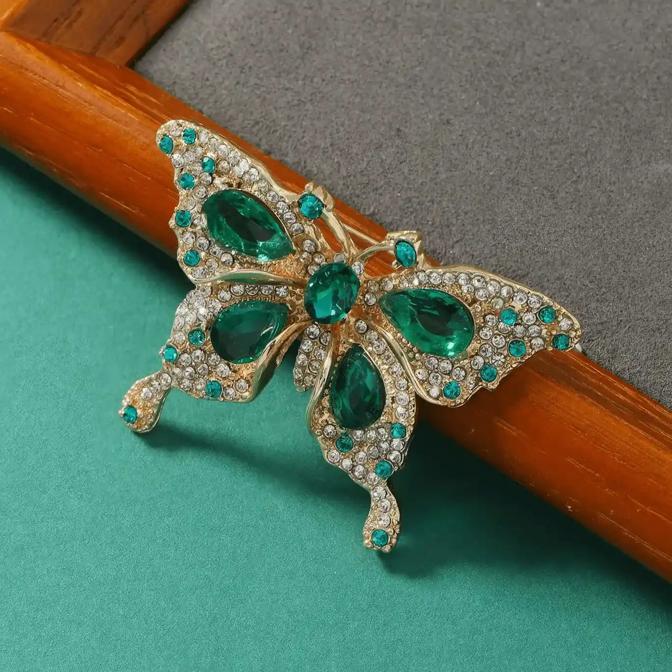 Side view of emerald jade butterfly brooch, green background, emphasizing design