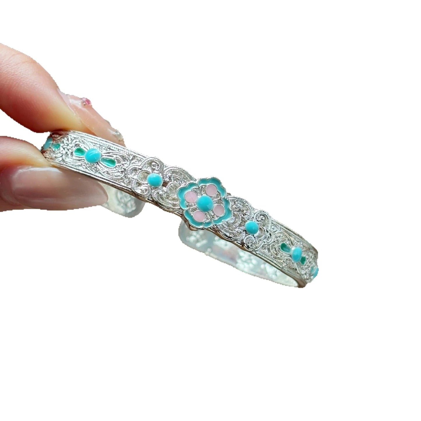 Hand holding enamel open bangle, showcasing design, white background