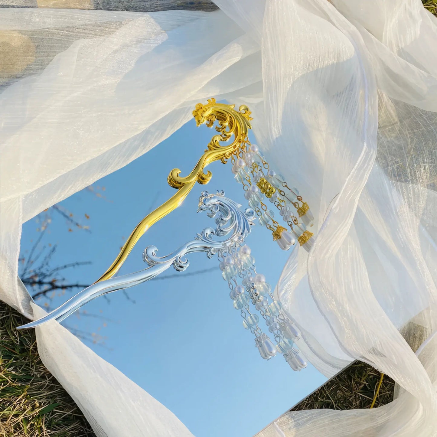 Fengjiu hairpin, gold and silver with pearl tassels, against blue sky and white fabric