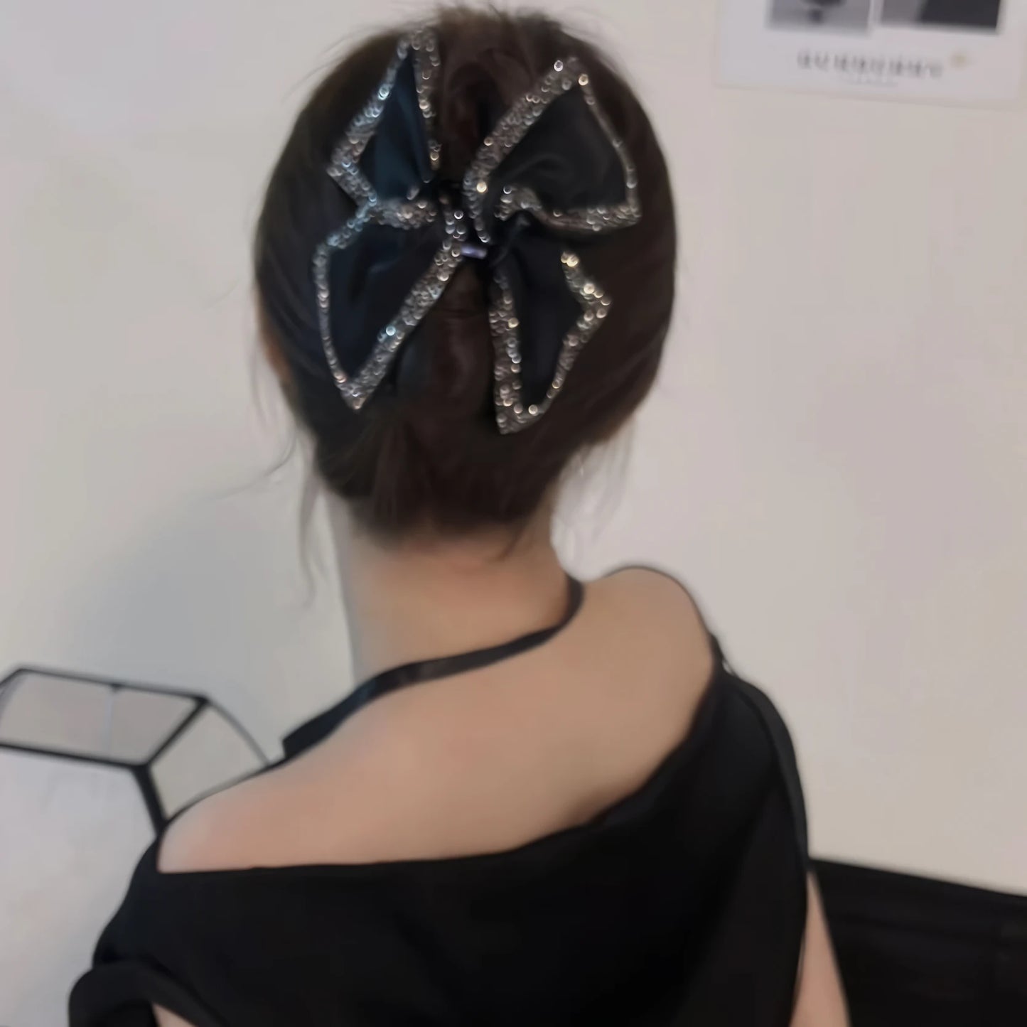 French Hedy style claw clip worn in an updo hairstyle, black clothing background, side view