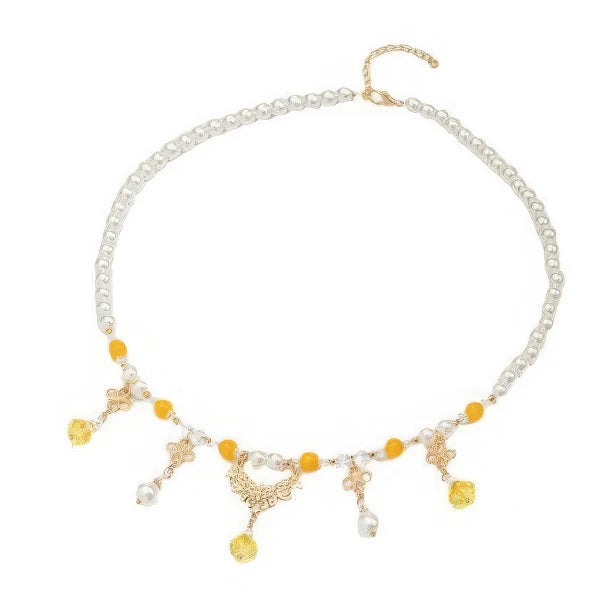 Gold - sprinkled pumpkin necklace with pearls and yellow beads, displayed on light surface