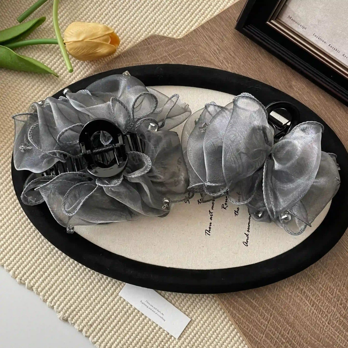 Two gray cloud bubble claw clips displayed on a round mat, light background with flower
