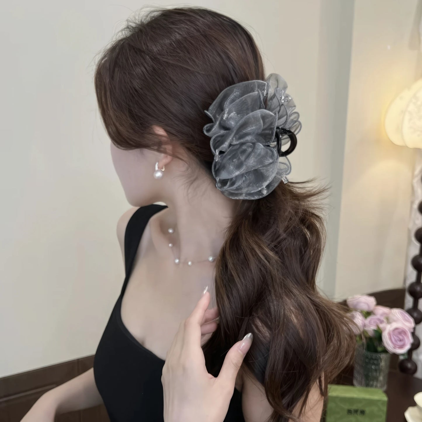 Gray cloud bubble claw clip worn in a half - up hairstyle, black clothing background