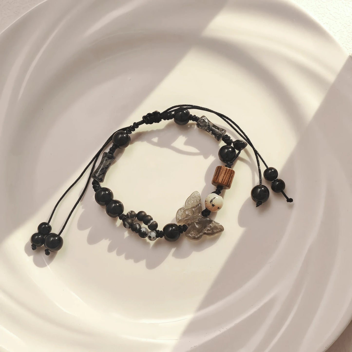 Ink wash butterfly beaded bracelet placed on white plate, emphasizing design